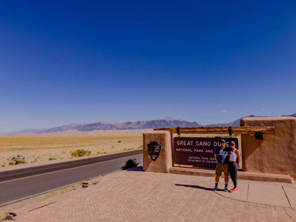 Lance & Carrie at Great Sand Dunes Entrance Sign — Great Sand Dunes National Park, Colorado (2026)